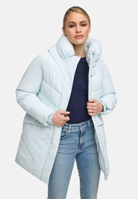 Gaiši zilā pūkaina jaka ar augstu apkakli, ribotām piedurknēm un rāvējslēdzēju priekšā. Iezīmēšanai ir izmantota quilted audums un brīva piegriezuma. Uzvilkta virs tumši zilā topa.