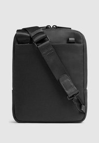 Zwarte crossbodytas van gestructureerde stof, met een verstelbare riem, ritssluiting en minimalistisch ontwerp zonder extra hardware.