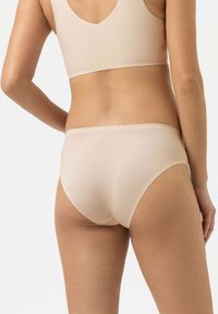 Beige naadloze onderbroek met een gladde textuur, lage taille en minimalistische afwerking. Bevat een subtiele merkafdruk op de achterkant.