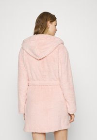 Pink hooded bathrobe made of soft, fluffy fabric, featuring a belted waist and long sleeves. The back showcases the textured material.