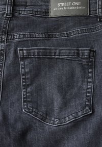 Mörka denimjeans med en fyrkantig bakficka. Tyget visar subtil textur och en jämn finish. Lappen visar "STREET ONE, all time favourite denim."