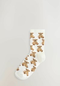 Weiße Socken mit wiederholtem Teddy-Bären-Muster in Beigetönen und Braun, aus weichem Material mit geripptem Bündchen.