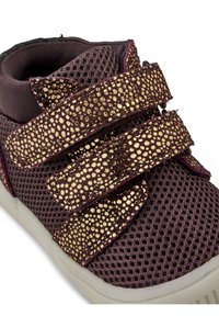 Zapatilla de malla morada con tres amplias correas de velcro de textura con manchas doradas, un collar acolchado y una suela de goma blanca.