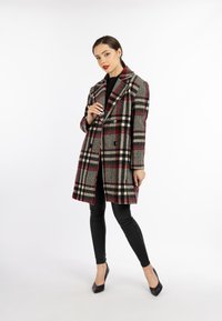 Rute uldfrakke i rød, sort og creme farver. Dobbeltbrystet design med store reverser og to forlommer. Sammen med sorte leggings.