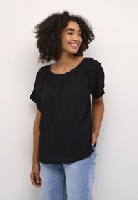 Sort kortærmet top med en samlet halsudskæring, lavet af letvægtsstof, med en afslappet pasform og subtil tekstur. Kombinationen er med lyse denim.