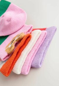 Stak af foldede strikkede sokker i pink, orange, hvid og lilla med et brunt bjørnehoved motiv på en pink sok.