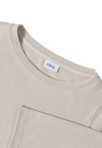 Beige crewneck sweater with a smooth texture and "CECIL" brand label sewn inside the neckline.