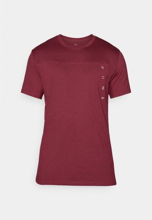 Red short-sleeve T-shirt made of soft fabric featuring a crew neckline and a logo printed vertically on the left side.