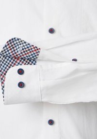 Weißes Hemd mit einem blau karierten Manschetten, das mit roten und blauen Knöpfen ausgestattet ist. Der Stoff ist glatt, und das Design der Manschette sorgt für einen Kontrast.