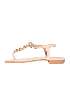 Sandalo piatto beige con cinturino tra le dita e cinturino alla caviglia, decorato con ornamenti scintillanti in oro e pietre preziose trasparenti sulla fascia superiore.