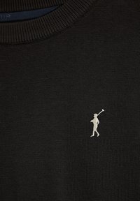 Svart stickad tröja med en liten vit broderad figur som håller en golfklubba på den övre vänstra sidan. Enkel ribbad halsringning.