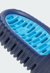 Blå plastkam med ett texturerat handtag i marinblått grepp och ett rillad design, med utskärningar för förbättrad luftflöde och enklare styling.