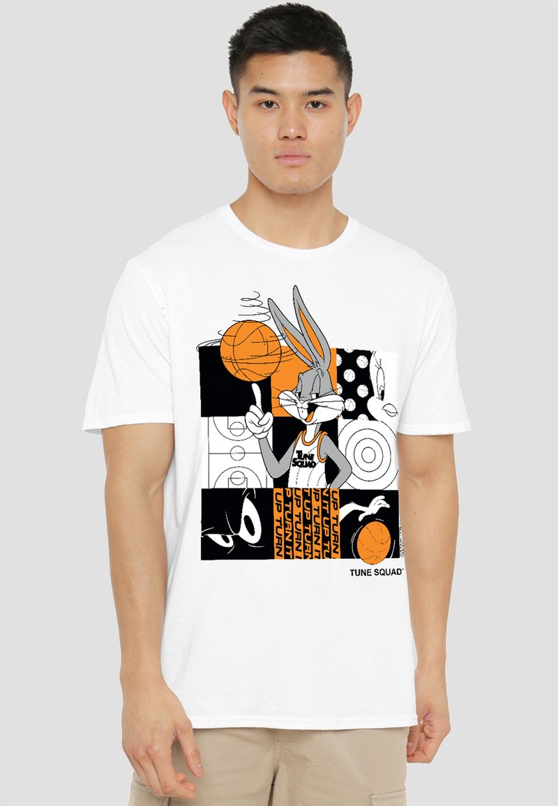 Young man wearing white T-shirt with Bugs Bunny spinning basketball and "Tune Squad" print in black and orange blocks.