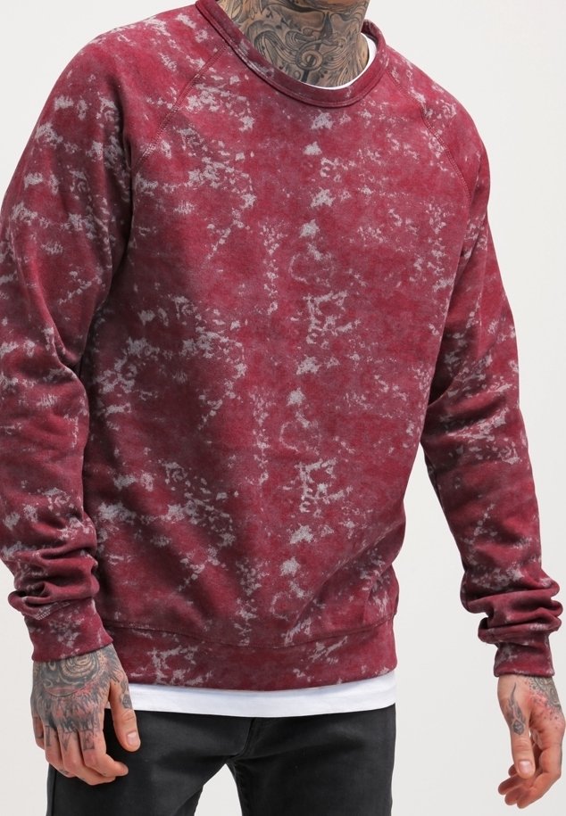 Sudadera de cuello redondo en color marrón con un patrón texturizado y desvaído. Presenta mangas raglán y un cuello y dobladillo ribeteados. Tejido suave.