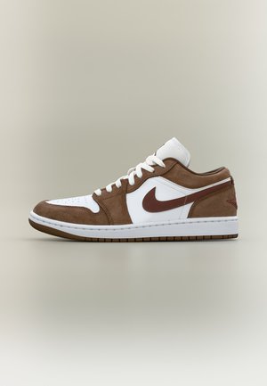 Baskets basses avec base en cuir blanc et empiècements en daim marron, lacets blancs et logo Nike marron sur le côté.