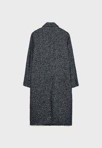 Cappotto a scacchi bianco e nero con maniche lunghe, colletto e taglio a lunghezza media. Presenta un tessuto texturizzato.