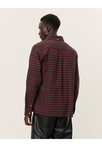 Camicia di flanella a quadri rossi e verdi con colletto a camicia, maniche lunghe e polsini con un bottone, realizzata in tessuto morbido e testurizzato.