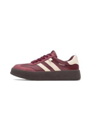 Zapatilla marrón con parte superior de cuero suave, rayas crema, punta redonda, suela de goma texturizada y cuello acolchado. Presenta cordones redondos y detalle del logo.