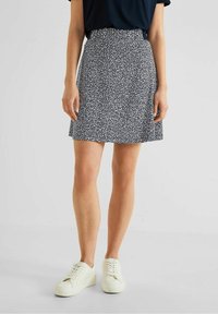 Sukně typu skater vzorovaná v námornické modři s bílým abstraktním designem. Elastický pás a volný střih, v kombinaci s bílými teniskami.