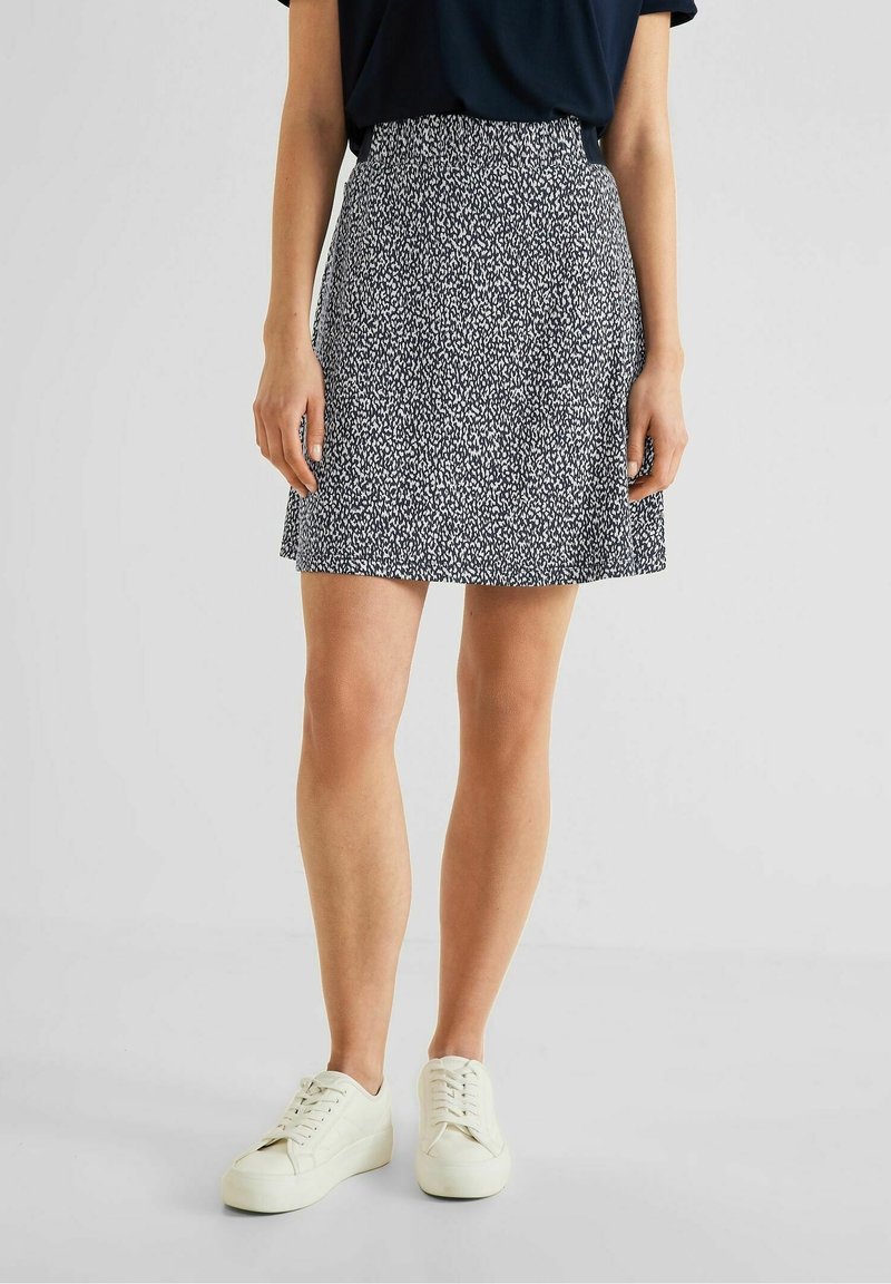 Sukně typu skater vzorovaná v námornické modři s bílým abstraktním designem. Elastický pás a volný střih, v kombinaci s bílými teniskami.