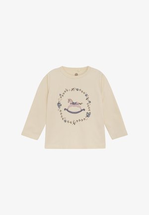 Langærmet cremefarvet skjorte med et gyngende hestemotiv omgivet af blomsterprint i forskellige farver, lavet af blødt stof.