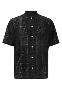 Camisa negra de manga corta con un diseño de encaje que presenta patrones cuadrados, logotipos sutiles y cierre de botones. Textura ligera y transparente.