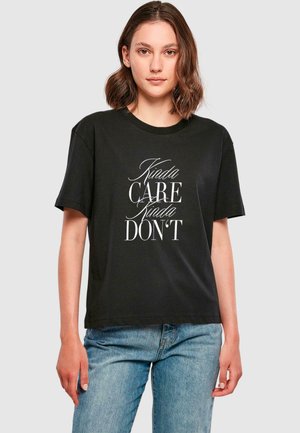 Svart bomullströja med korta ärmar som har texten "Kinda CARE Kinda DON’T" i vit stiliserad typografi över framsidan.