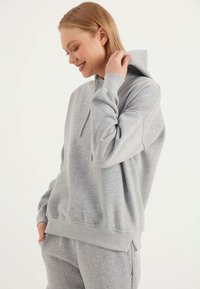Hellgrauer Sweatshirt mit verstellbarem Kapuzenzug, gerippten Bündchen und Saum. Hergestellt aus weichem, strukturiertem Stoff und mit lockerer Passform.