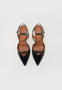 Sorte lærpointede sko med slingback-design, der har en lille sløjfedetalje og tan indlægssåler. Glat tekstur og minimalistisk stil.