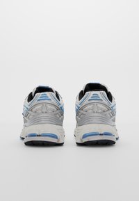 Grå och blå löparskor med en texturerad ovandel, andningsbar mesh, dämpad häl och svart gummisula. Bakifrån syns design detaljer.