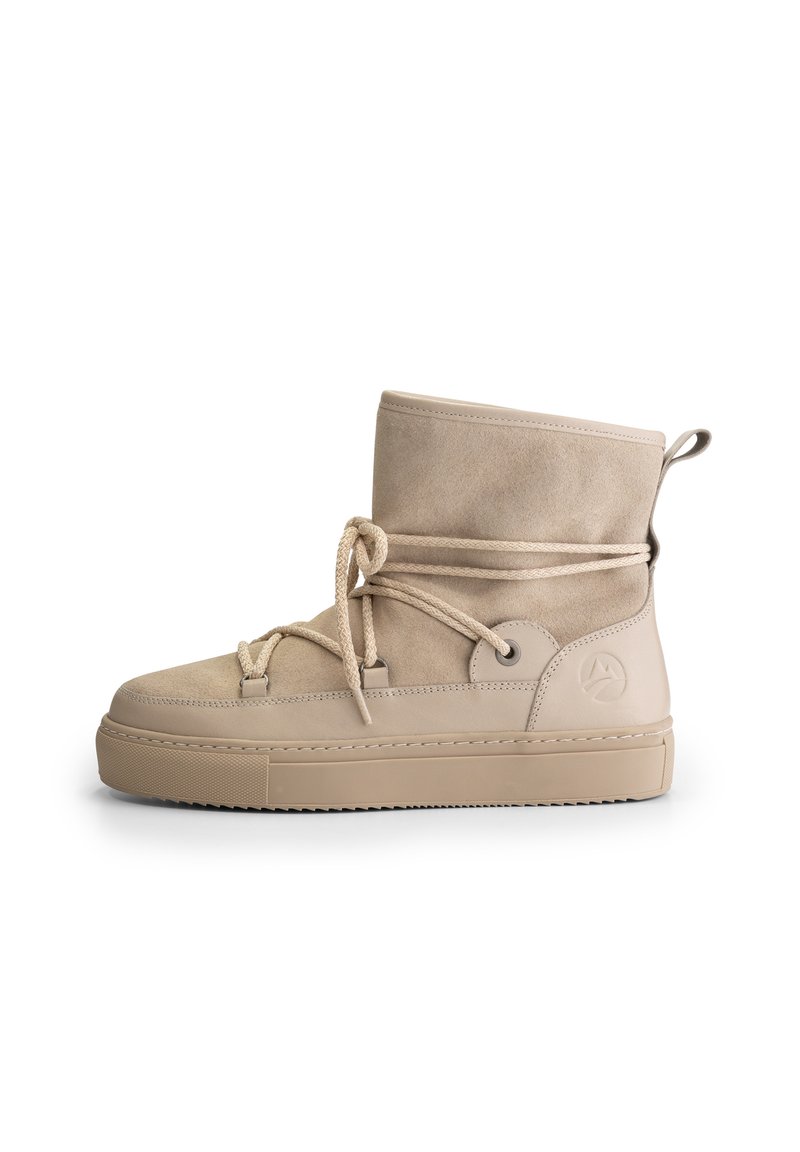 Beige suede ankle boot with thick rubber sole, lace-up front, pull tab at heel, and embossed logo on side.