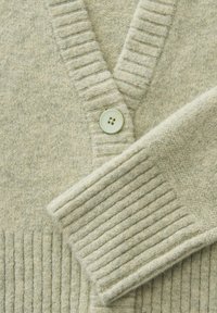 Lichtgroene wollen cardigan met een V-hals, geribbelde textuur op de mouwen en de zoom, met een enkele bleekkleurige knop nabij de hals.