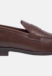 Braune Lederloafers mit glatter Textur, gestickten Details und angehobenen Riemen über dem Vorderfuß. Flache Sohle mit dezentem Branding.