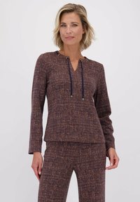 Gebreide top in donkerpaars met een gestructureerd patroon, met een V-hals en trekkoorden met metalen accenten bij de halslijn. Lange mouwen.