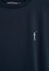 Polo bleu marine avec une petite icône de joueur de polo gris clair sur le côté gauche de la poitrine et le texte "Polo Club" sur l'étiquette du col.