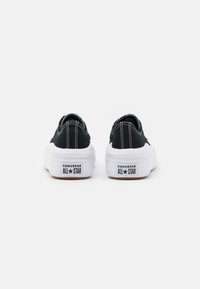 Zwarte canvas sneakers met witte rubberen zolen, voorzien van witte stiksels en een textuuraccent aan de achterkant met "CONVERSE ALL STAR"-branding.