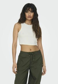Witte, cropped tanktop van ribgebreid materiaal, gecombineerd met losse, groene cargobroeken met een koord in de taille en zijzakken.