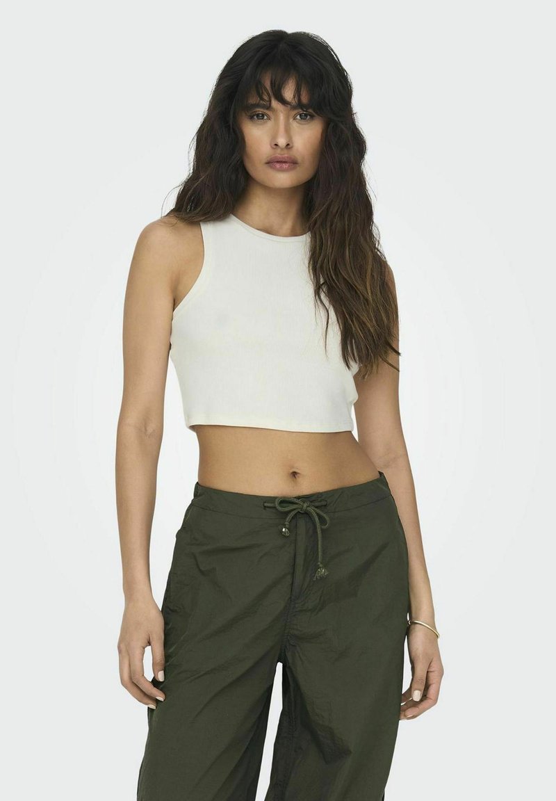 Witte, cropped tanktop van ribgebreid materiaal, gecombineerd met losse, groene cargobroeken met een koord in de taille en zijzakken.
