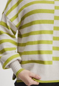Gestreifter Pullover in Creme und leuchtendem Grün. Weiches Strickmaterial mit breiten horizontalen Streifen, gerippten Bündchen und Saum, lockere Passform.