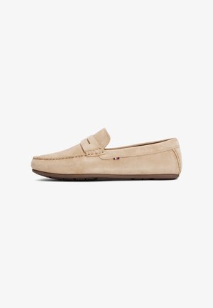 Beige semskede loafers med en sydd design, slip-on stil, og gummisåle. Har en liten logo aksent nær hælen.