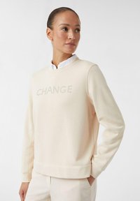 Felpa cremoso con testo "CHANGE" in strass, scollo rotondo, polsini e orlo a costine, realizzata in materiale morbido, vestibilità comoda.