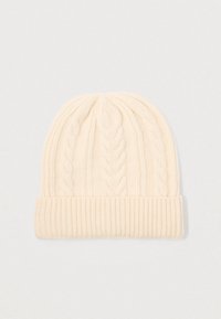 Cream-colored knitted beanie with folded ribbed brim and braided cable knit pattern on a plain white background.
