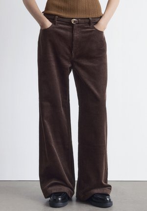Braune Cord-weitbeinige Hose mit strukturiertem Finish, ausgestattet mit Vordertaschen und einem schwarzen Gürtel mit einer goldenen Schnalle.