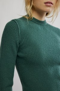 Grønn ribbestrikket genser med rund hals. Har en strukturert, myk overflate og en tettsittende silhuett som fremhever kroppens form.