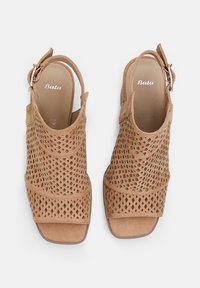 Tan nahkased slingback kontsad, millel on teemantkujundusega lõiked, avatud varvaste disain ja reguleeritav pahkluu rihm. Sile sisemine vooder.
