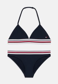 Marine bikini-sæt med trekantet top og matchende underdele. Har en hvid stribe, der fremhæves med røde og hvide bånd. Glat stoftekstur.