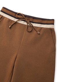 Brązowe dresy z troczkami w pasie, z paskiem w kolorze ciemnobrązowym i beżowym. Wykonane z miękkiego, strukturalnego materiału.