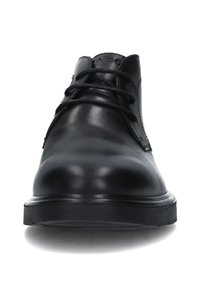 Scarpe in pelle nera con una texture liscia, punta tondeggiante, design con lacci e dettagli minimalisti. Suola piatta in gomma nera.