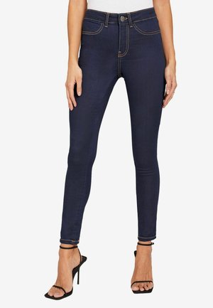 Vysoké džíny skinny v tmavém odstínu vyrobené z denimu, s kontrastním žlutým prošíváním a klasickým pětizásuvkovým designem.