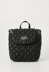 Schwarze gesteppte Handtasche mit strukturiertem Design, ausgestattet mit einem oberen Griff, goldenen Beschlägen und einem Logo-Schild auf der Vorderseite. Texturierte Oberfläche.